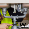A plumber in Castle Rock, CO is fixing a sink under a counter.