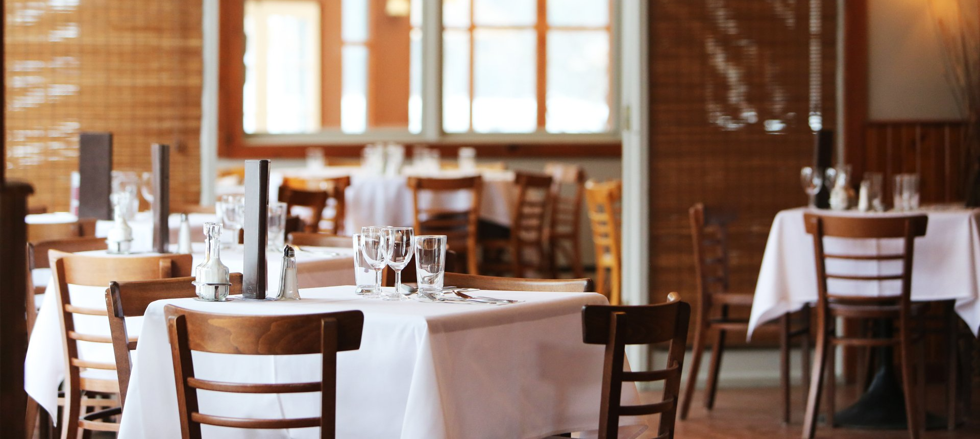 Un restaurant vide avec des tables et des chaises dressées pour un repas.