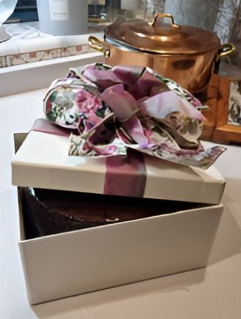 Un pastel en una caja con un lazo morado.