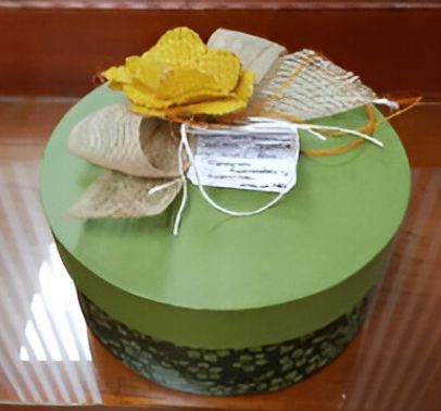 Una caja verde con una flor amarilla encima.