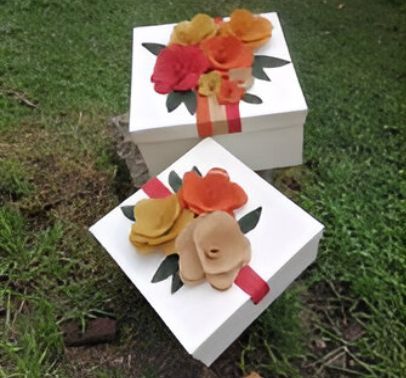 Dos cajas blancas con flores están en el césped.