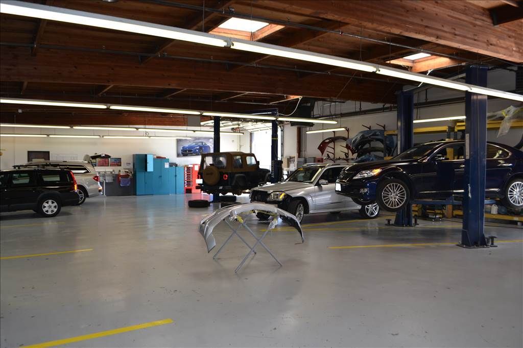 a man is using a tablet in a garage next to a car .