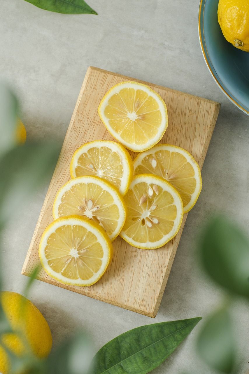 Sliced lemons are sitting on a wooden cutting board.