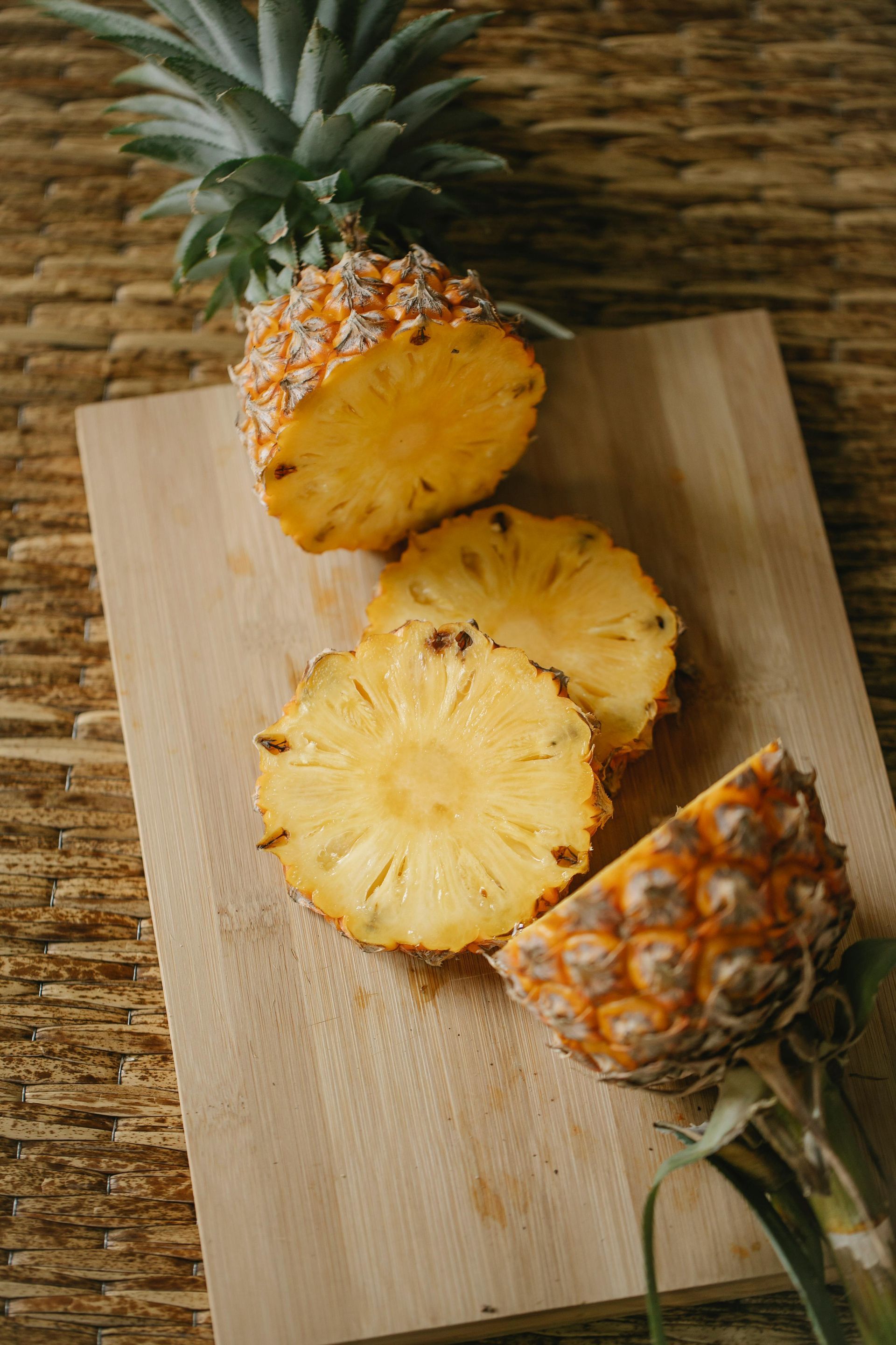 A pineapple cut in half on a wooden cutting board.