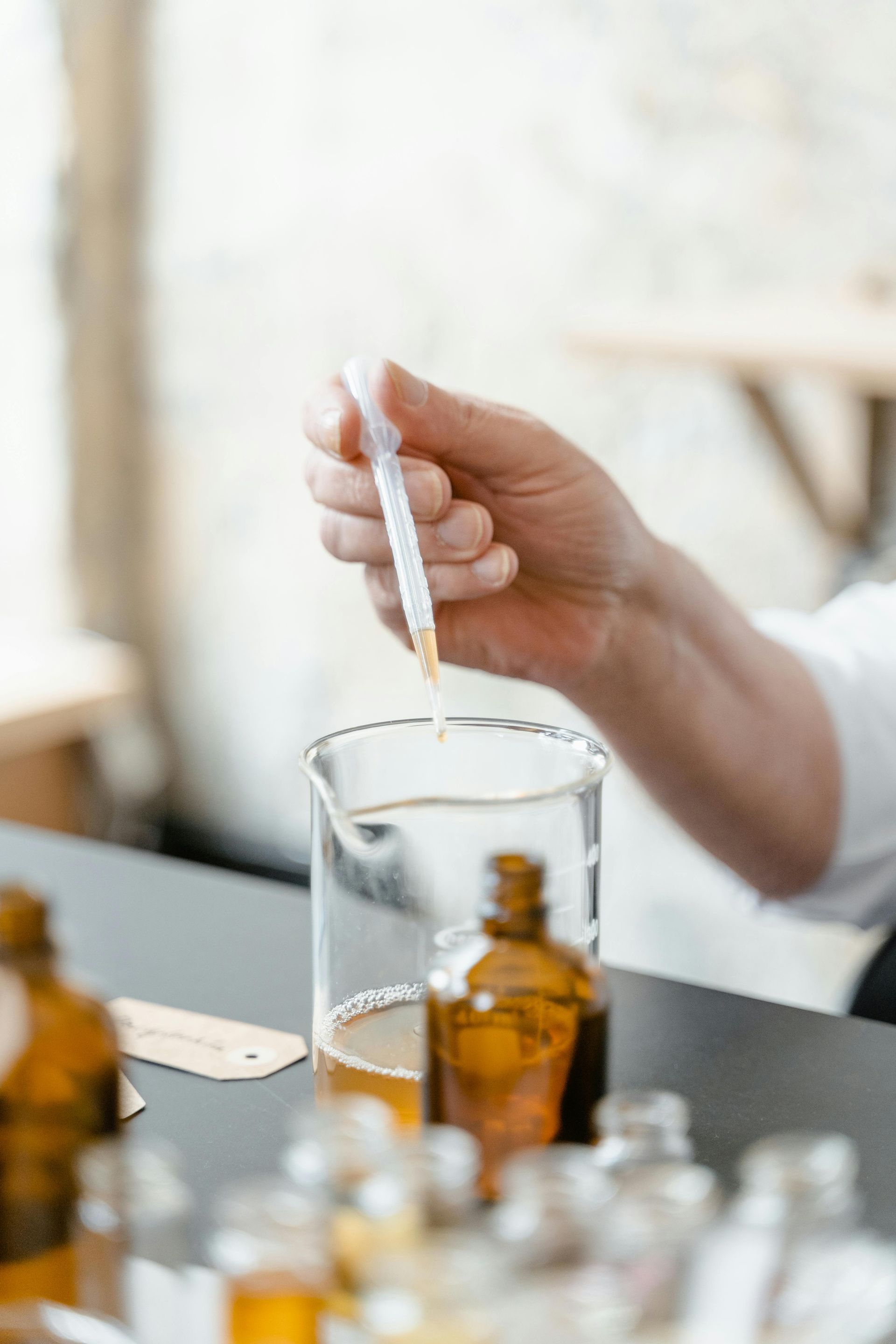 A person is pouring liquid into a beaker with a pipette.