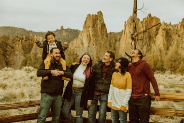 A group of people are standing next to a wooden fence.