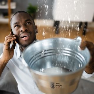 A man is talking on a cell phone while holding a bucket of water