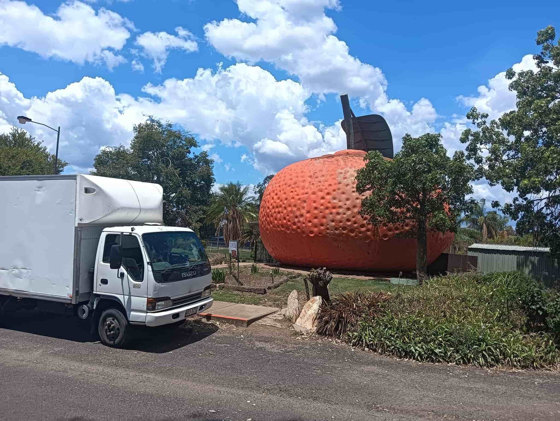 A white truck is parked in front of a large orange sculpture. — CM Removals & Transport In Maryborough, QLD