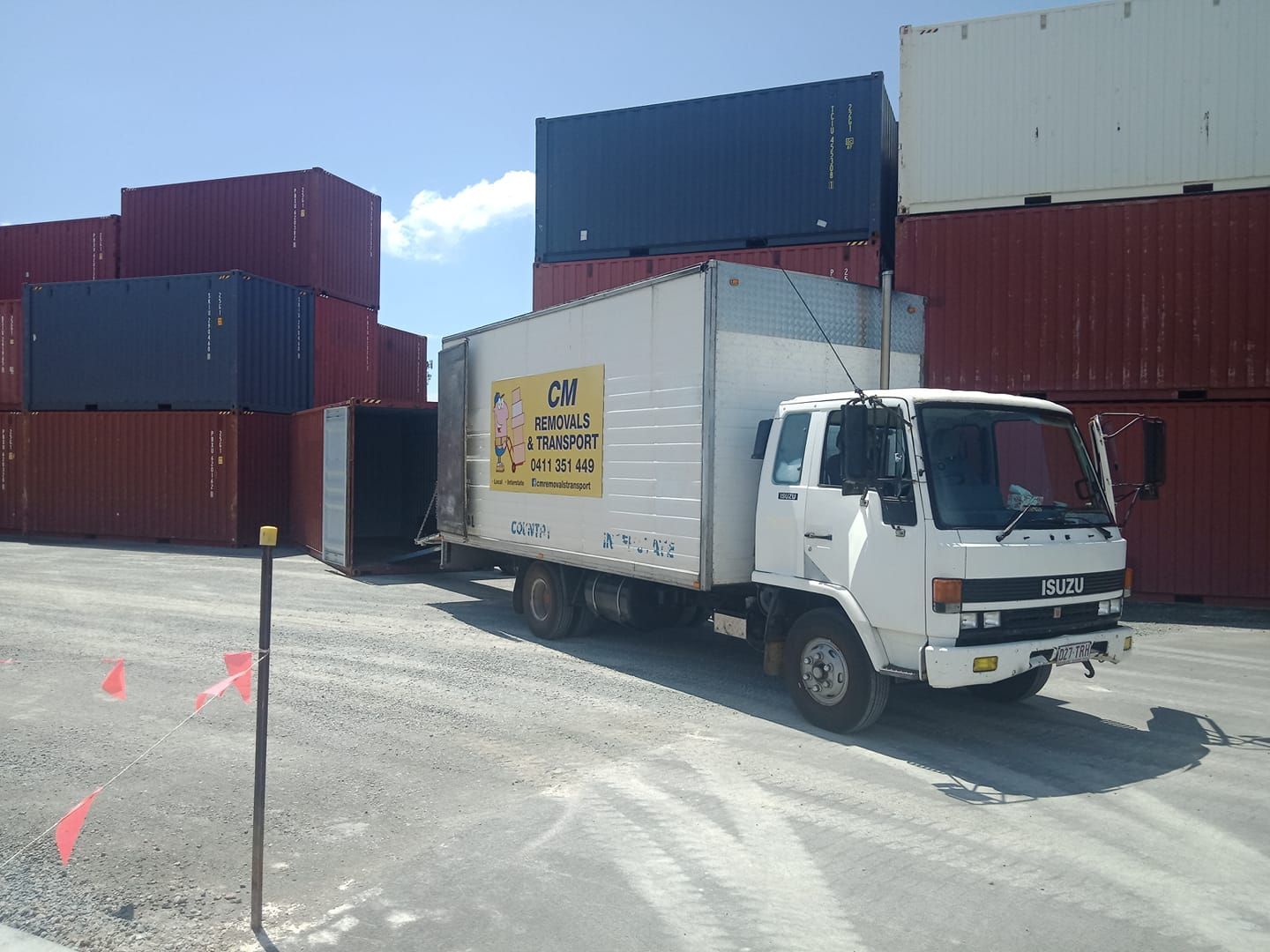 A white truck is parked in front of a stack of shipping containers — CM Removals & Transport In Sunshine Coast, QLD