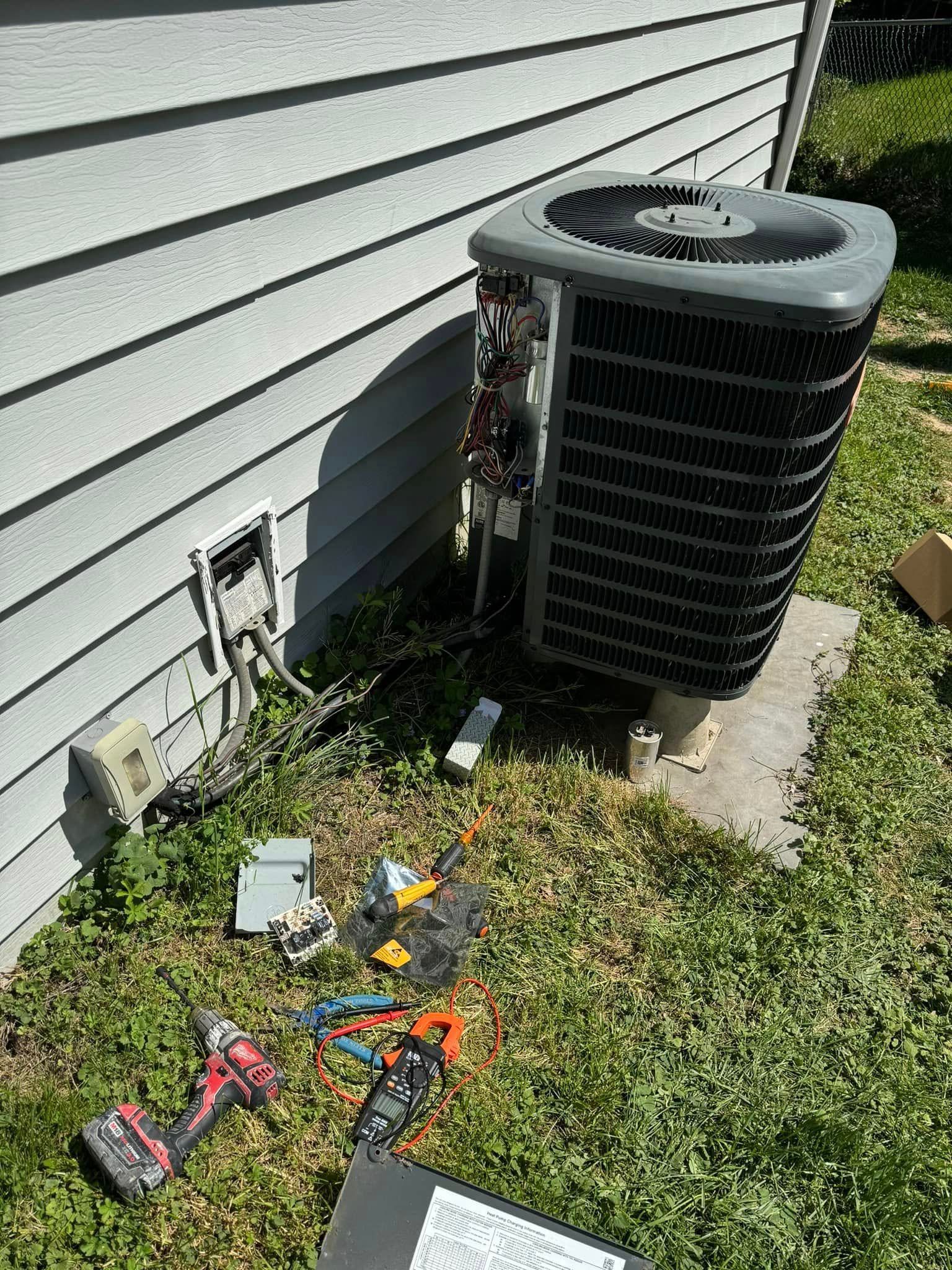 HVAC unit being worked on outdoors with tools on the ground.