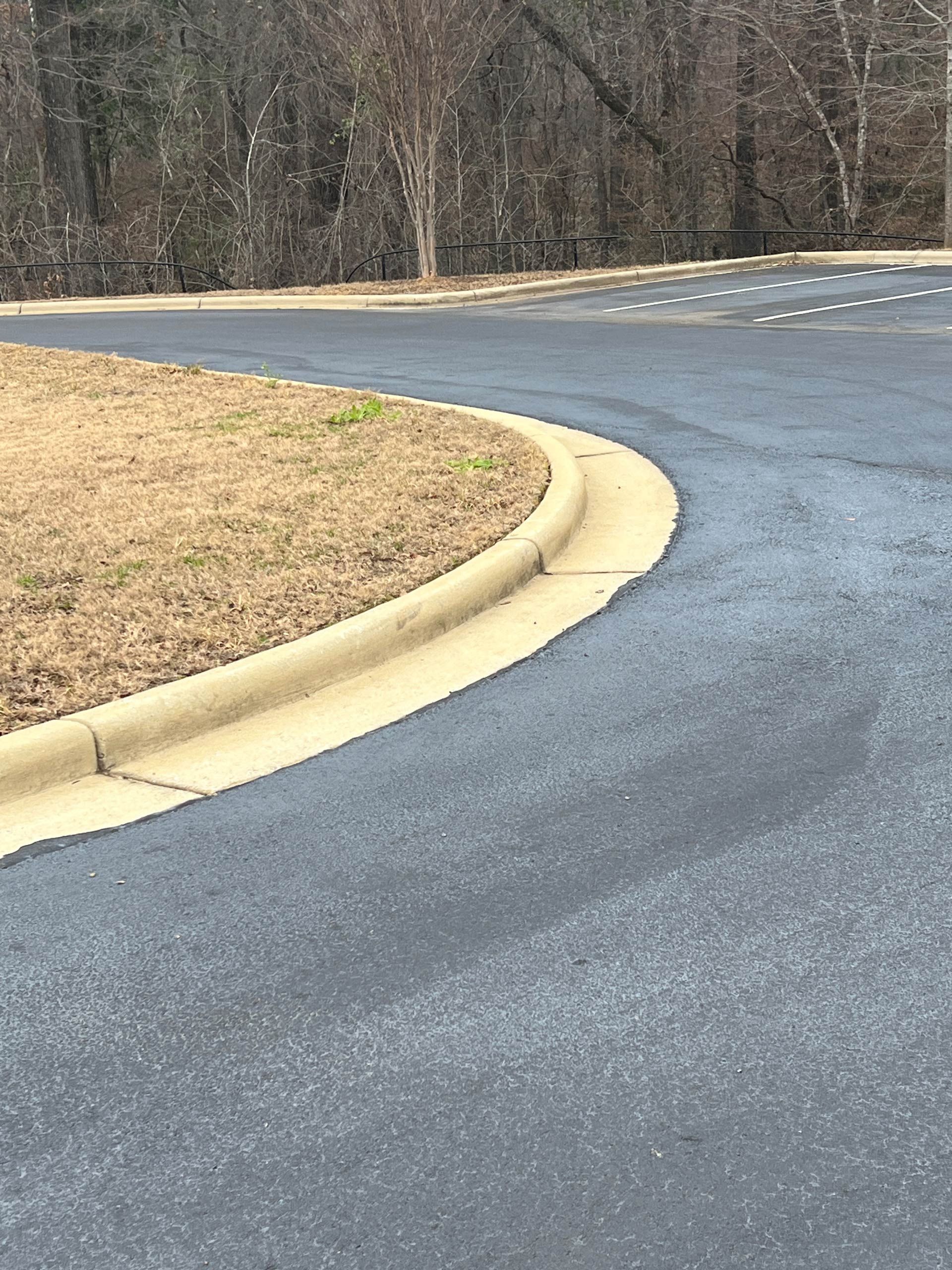 A close up of a road with a curb and grass on the side of it.