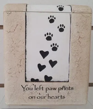 A box with paw prints and hearts that says you left paw prints on our hearts