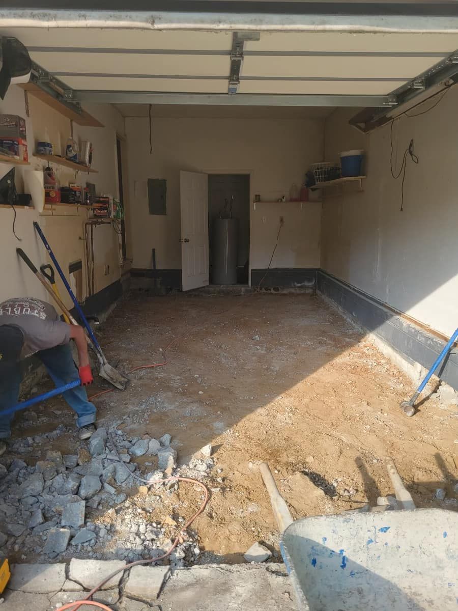 Garage with exposed dirt floor, water heater, and tools; under construction.