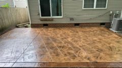 Brown stamped concrete patio next to house with sliding glass door.