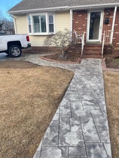 Gray paver walkway leading to a brick and beige house with a truck parked on the left.