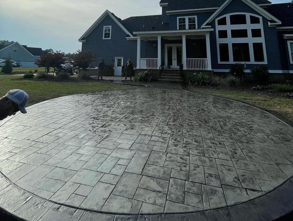 Circular patterned concrete patio in front of a blue house, with person in the foreground.