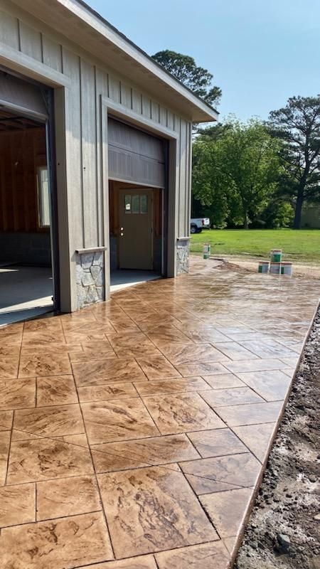 Brown stamped concrete patio outside a tan garage with open door.