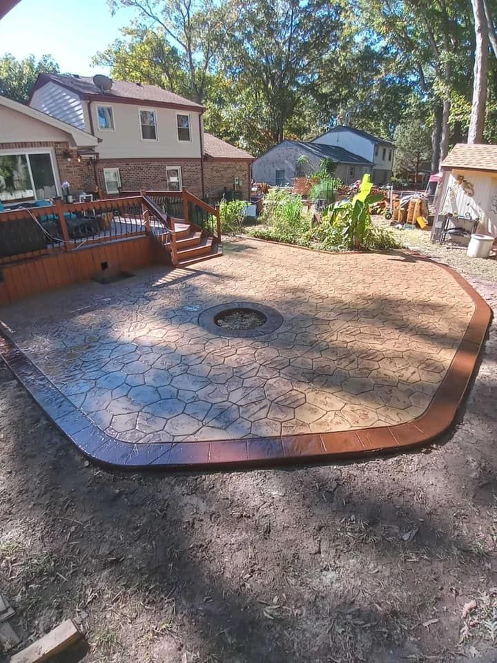 Backyard patio with stamped concrete, fire pit, and wooden deck; houses in the background.