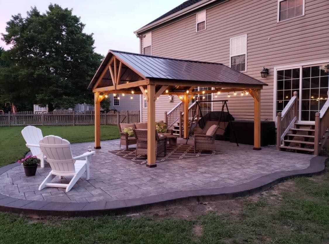 Backyard patio with a wooden gazebo, seating, and stamped concrete.