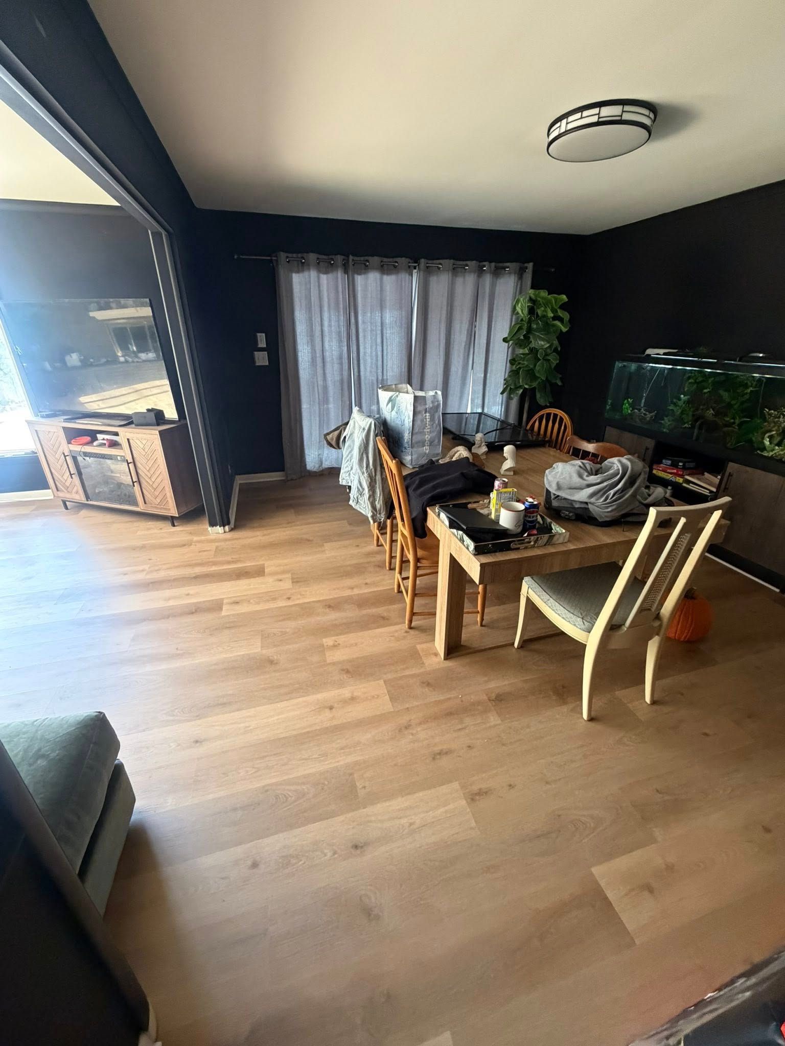 Dining room with wooden table and chairs, dark walls, large windows, and light wood flooring