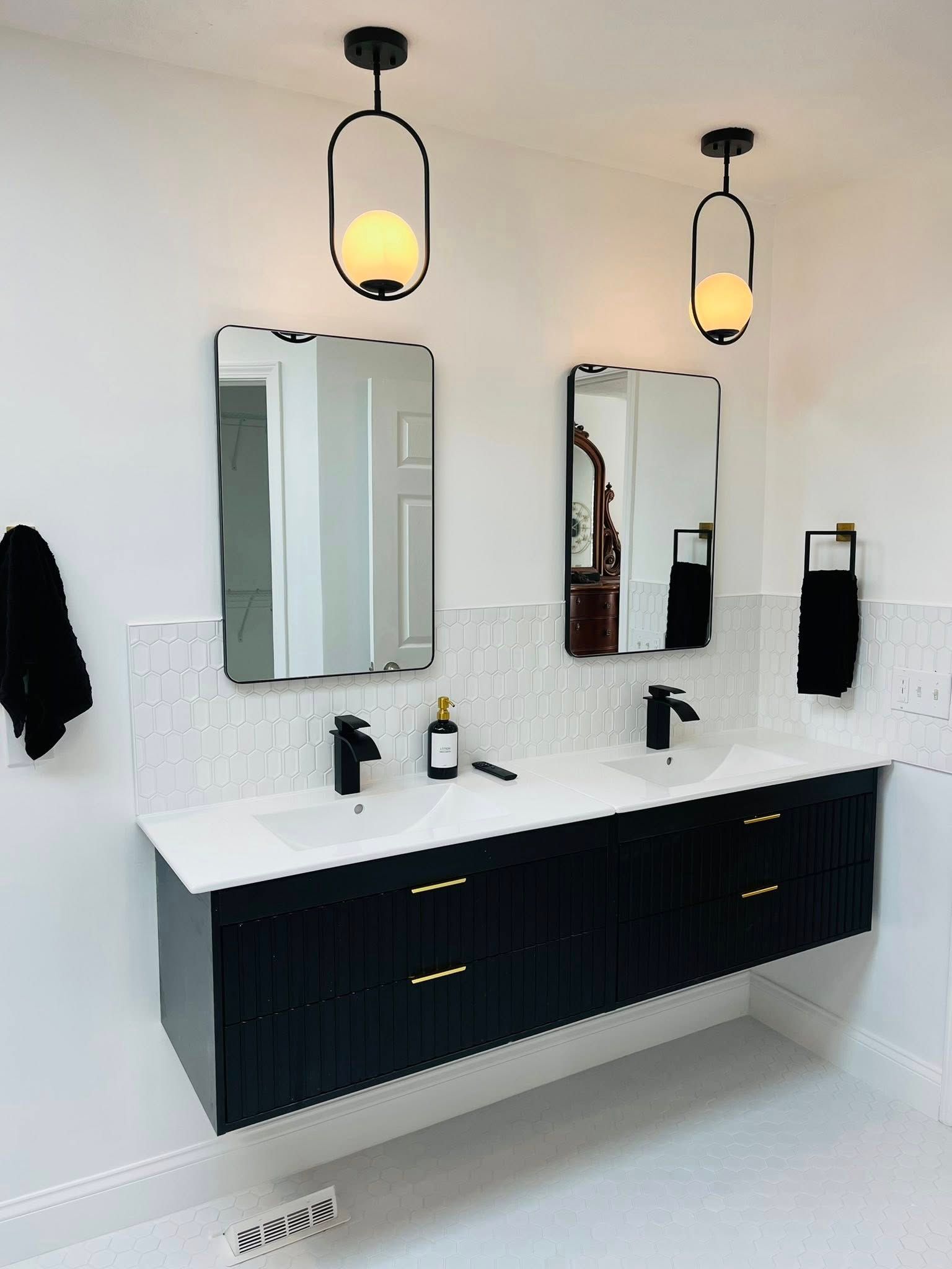 Modern black-and-white bathroom with double vanity, mirrors, sconces, and wall-mounted storage