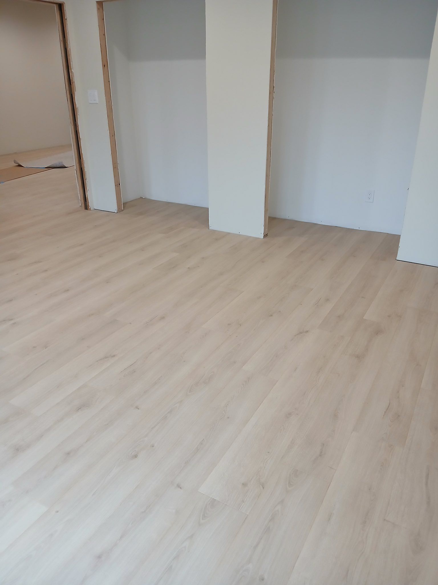 Empty room with light wood flooring and white walls, showing open closet alcoves.