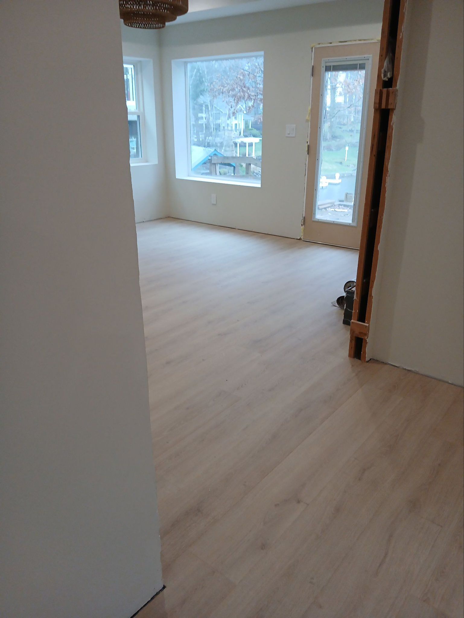 Empty bright room with light wood floors and large windows overlooking snow outside