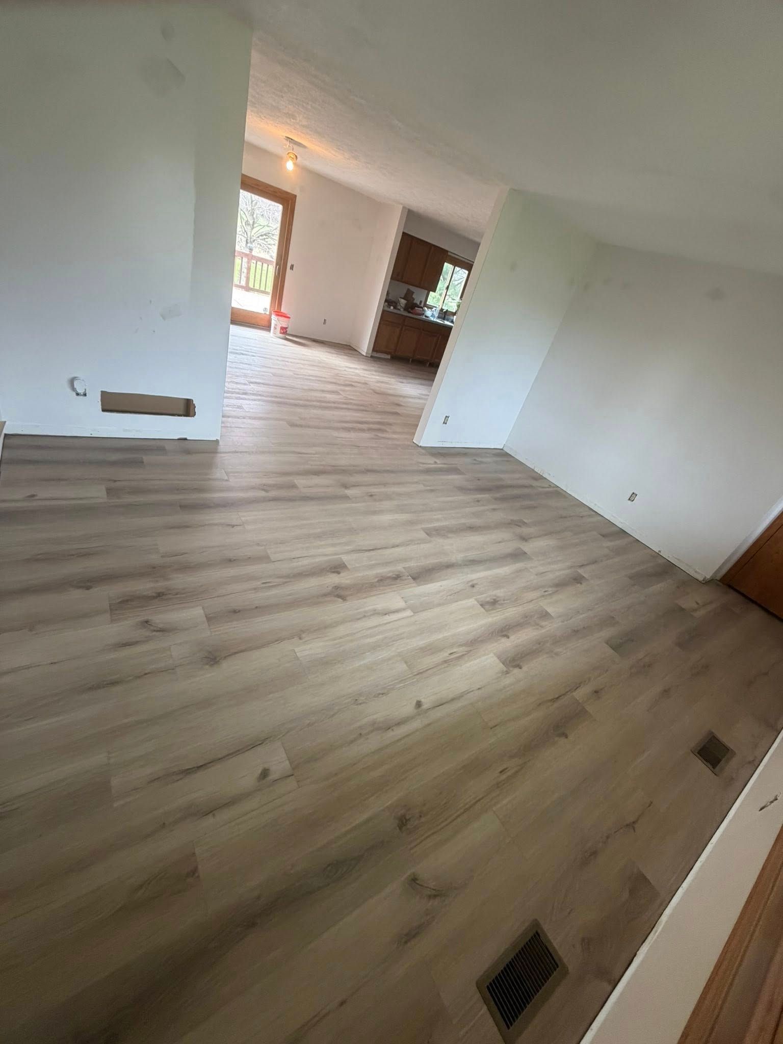Empty room with light wood floors, white walls, and an open doorway to another room.