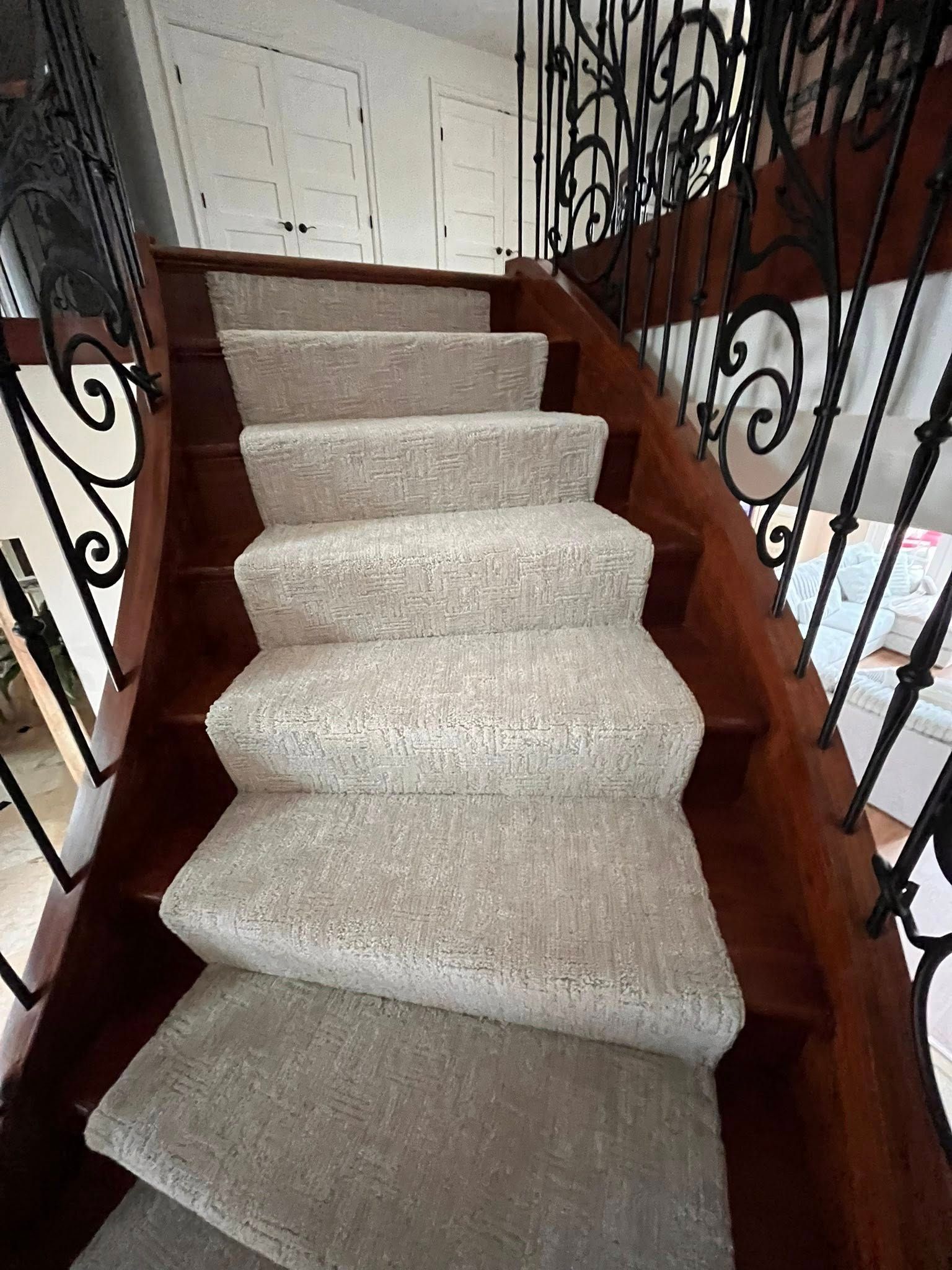 Carpeted staircase with wooden banisters and black wrought-iron railings indoors