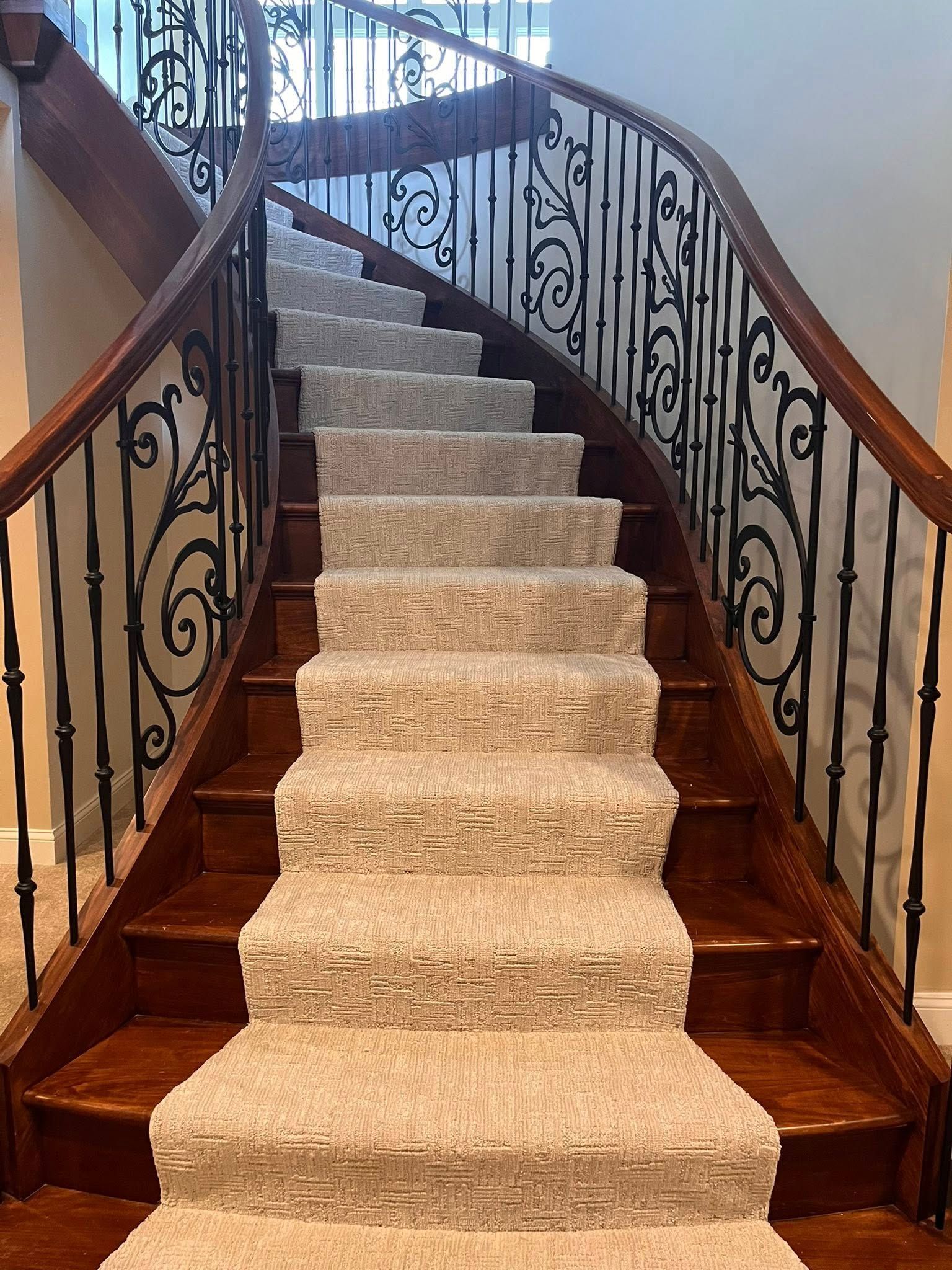 Carpeted staircase with ornate wrought-iron railings and wood steps in a home interior