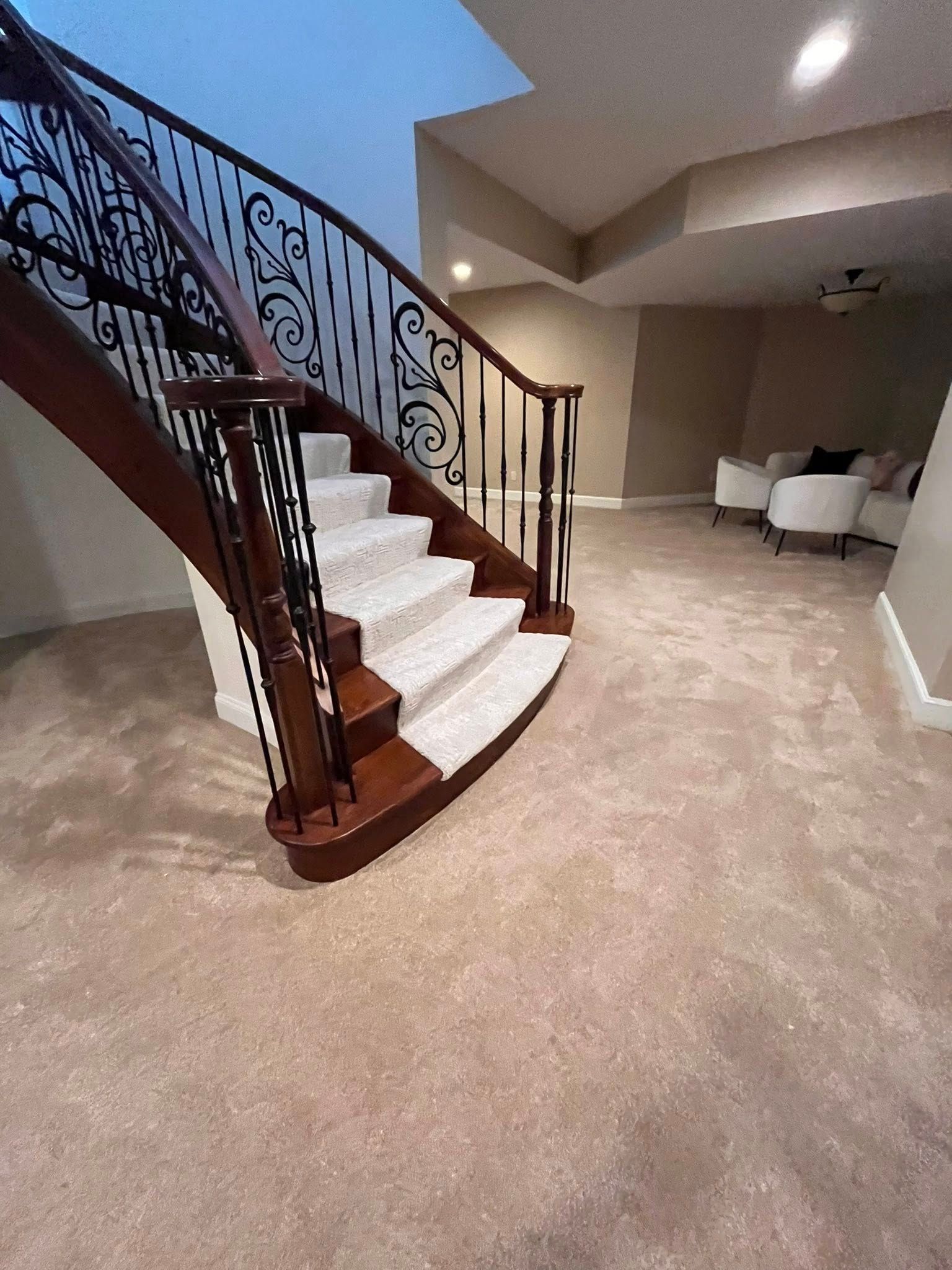 Carpeted staircase with dark wood railing in a beige living room, leading to an upper floor.