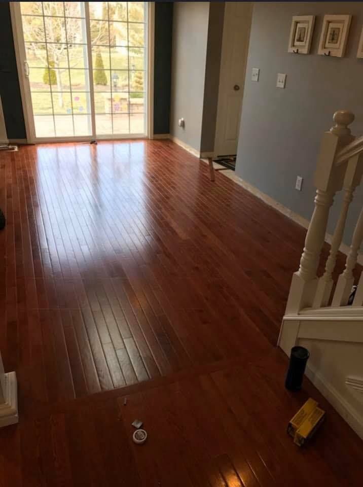 Empty hardwood-floored living room with sliding glass door and staircase on the right