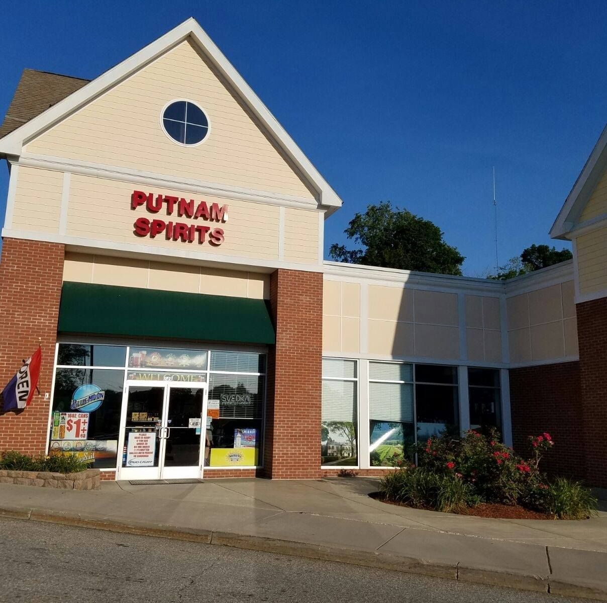 Putnam Spirits store exterior with red letters, green awning, and blue sky.