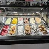 Ice cream display case with various colorful gelato flavors.
