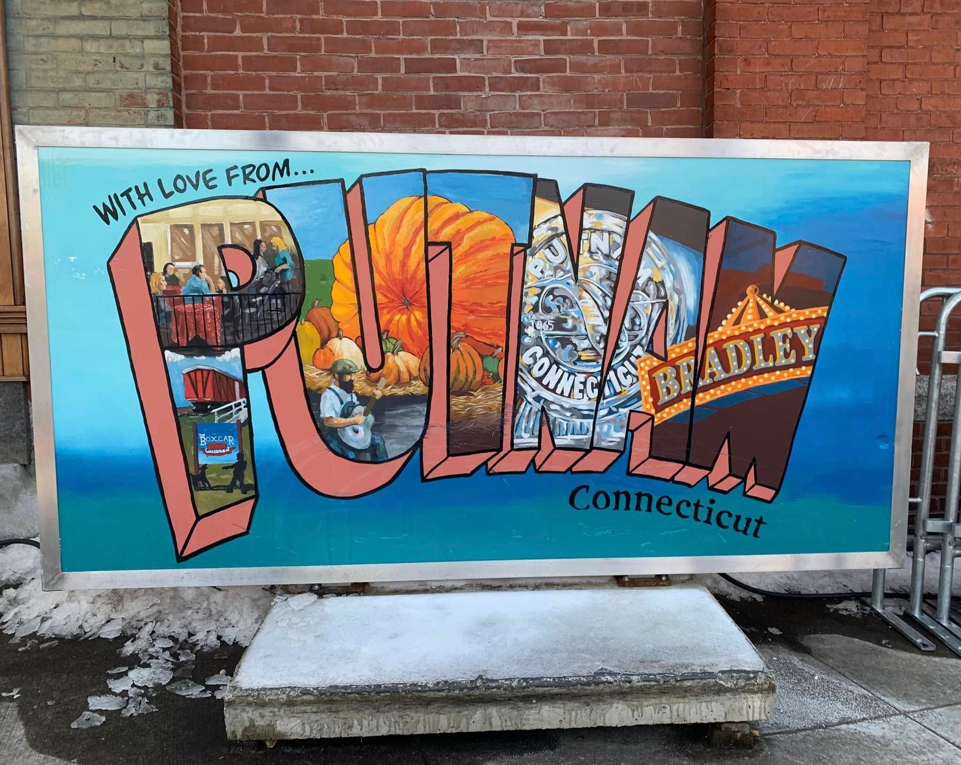 Large painted Putnam, Connecticut postcard sign with pumpkins, buildings, and Bradley Playhouse.