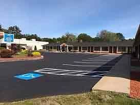 Exterior view of hotel and parking lot with a handicap accessible space. Blue sky.