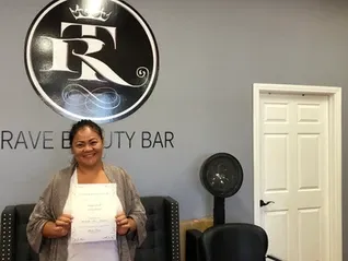 Happy woman near the door holding certificate | Sylmar, CA | Rave Beauty Bar
