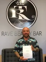 Man in green polo under logo holding certificate | Sylmar, CA | Rave Beauty Bar