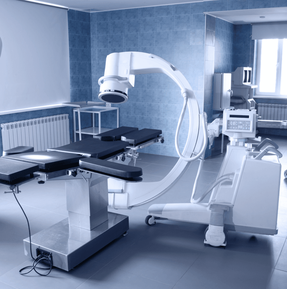 Medical operating room with a patient table and an X-ray machine.