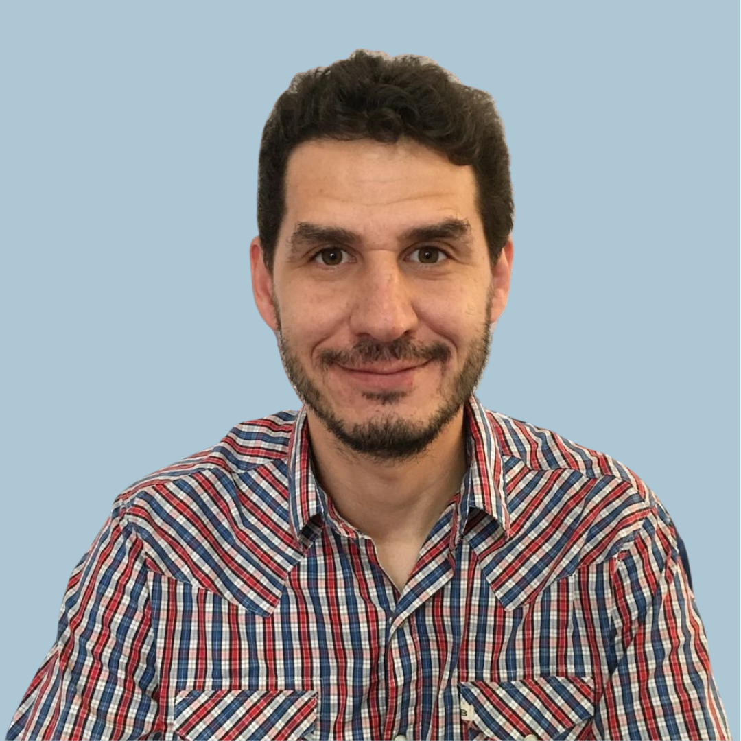 a man in a plaid shirt is sitting in a chair in front of a neon sign .