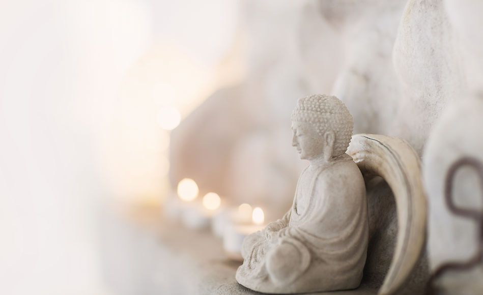 Stone Buddha statue with candles, peaceful setting, soft light.