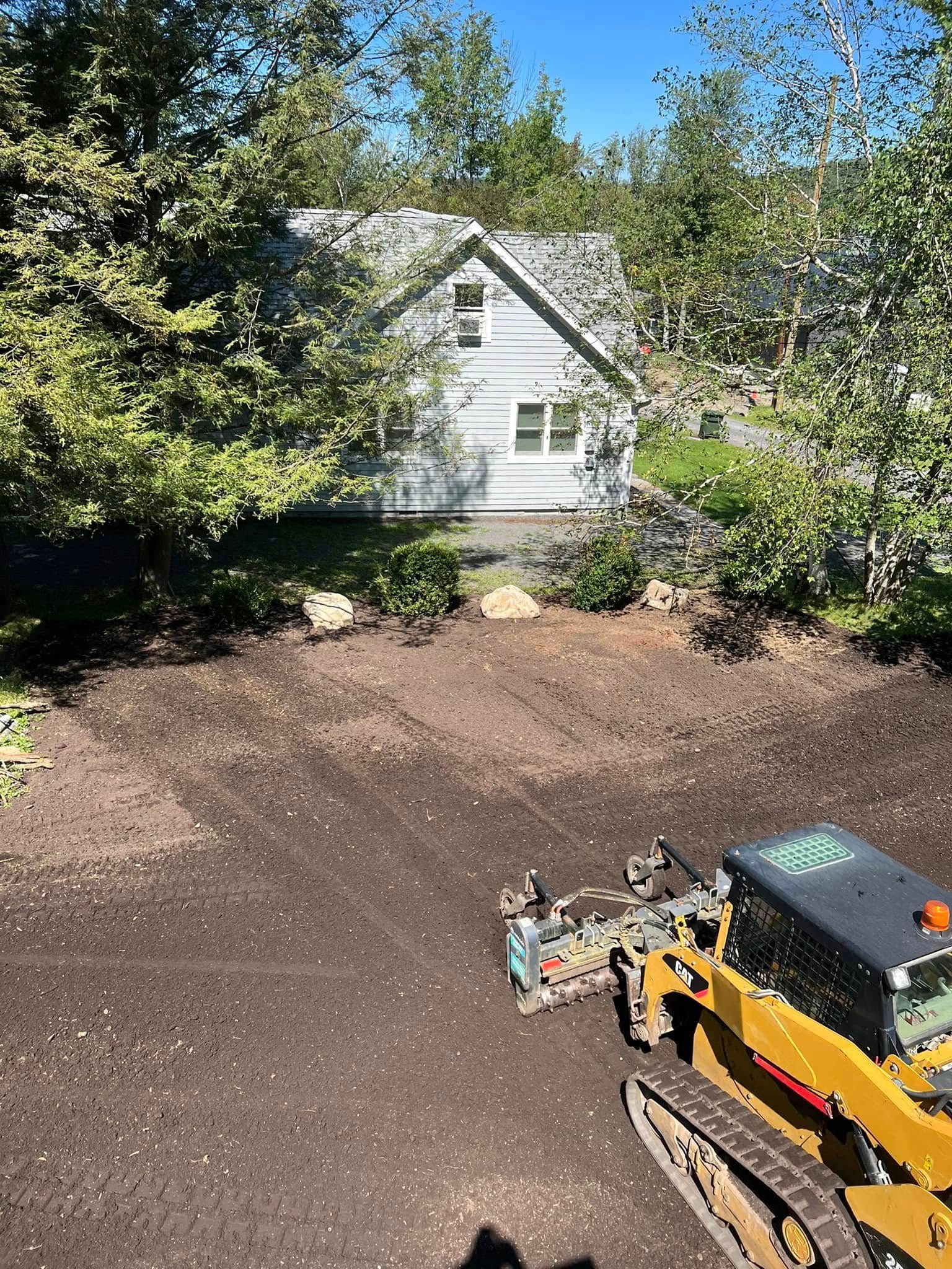 A bulldozer on a muddy clearing surrounded by trees.