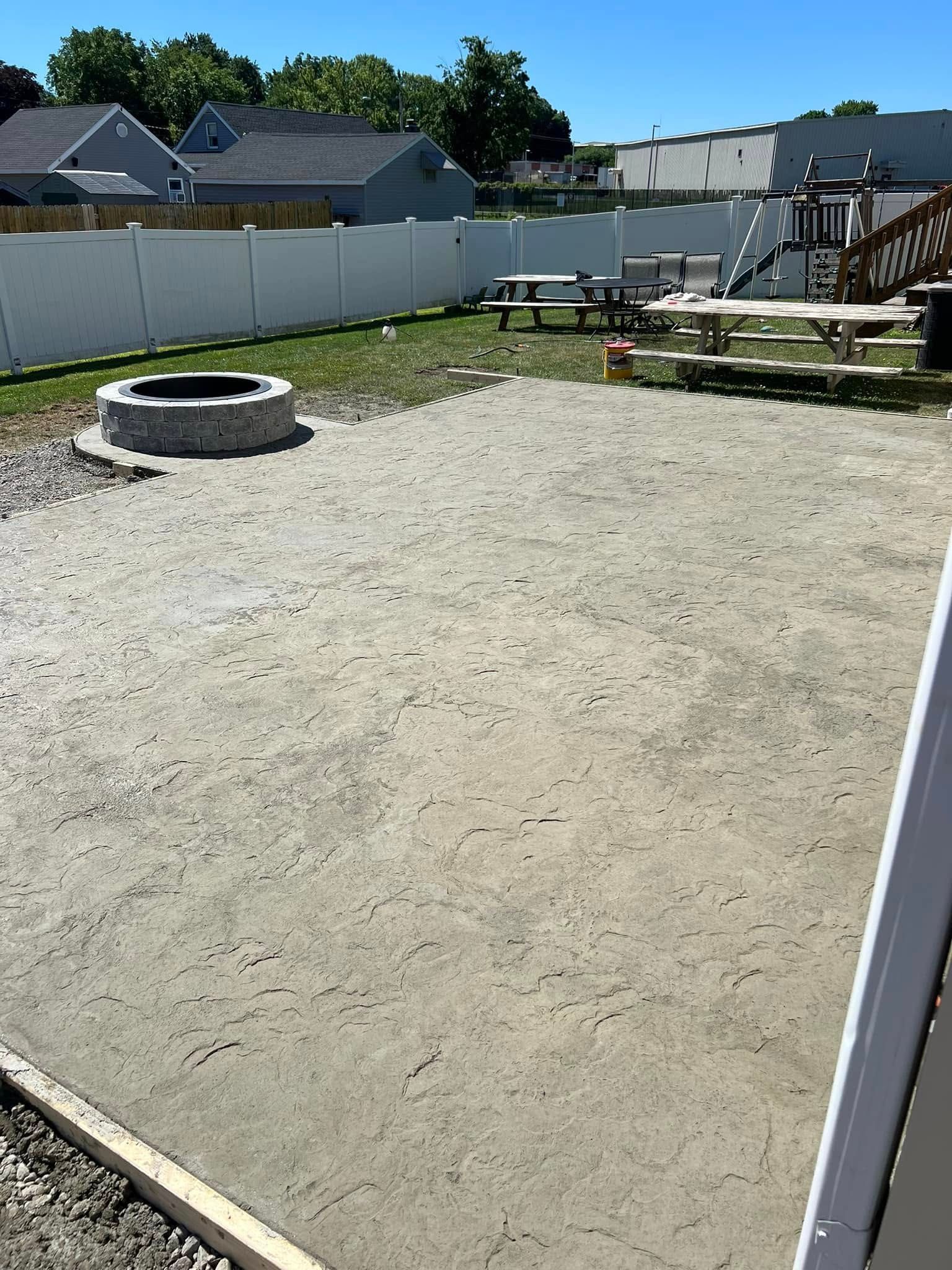 Freshly poured concrete slab with embedded metal pins, on a dirt surface.