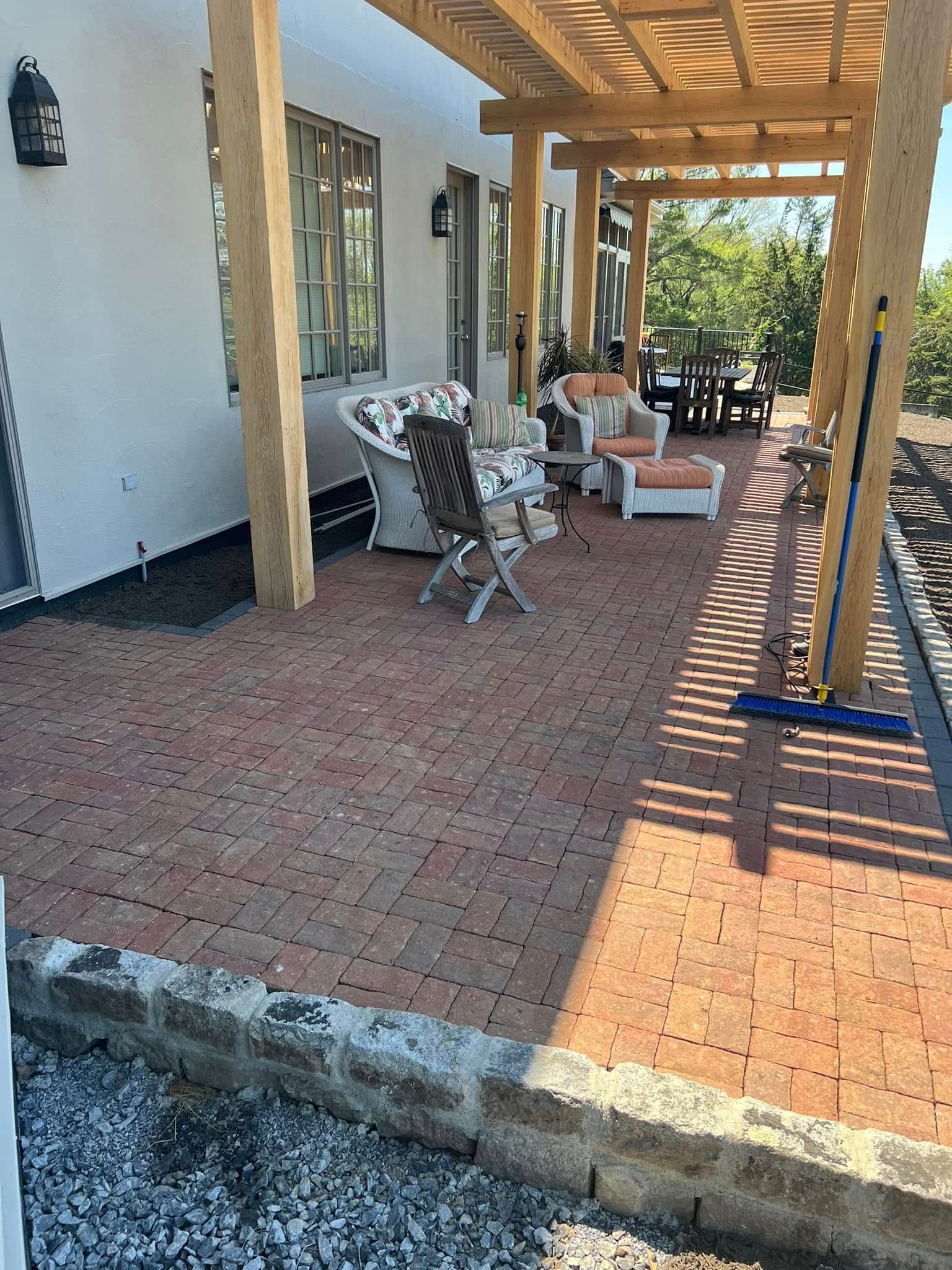 Brick patio with wooden pergola, outdoor seating, and white stucco building.