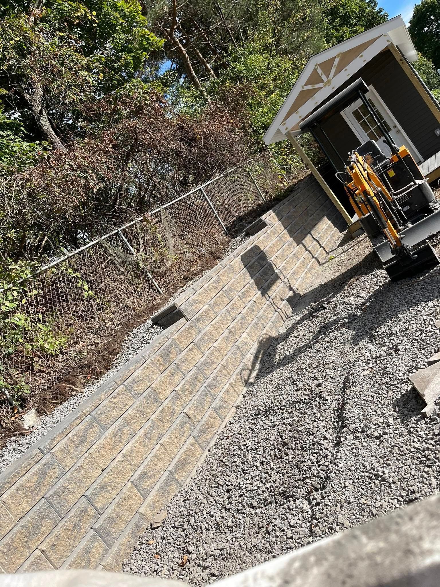Retaining walls with plants and a green lawn. Wooden fence in background.
