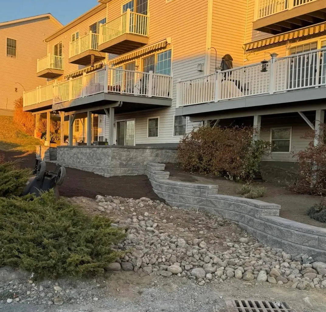 Gray block retaining wall with gravel and dirt.