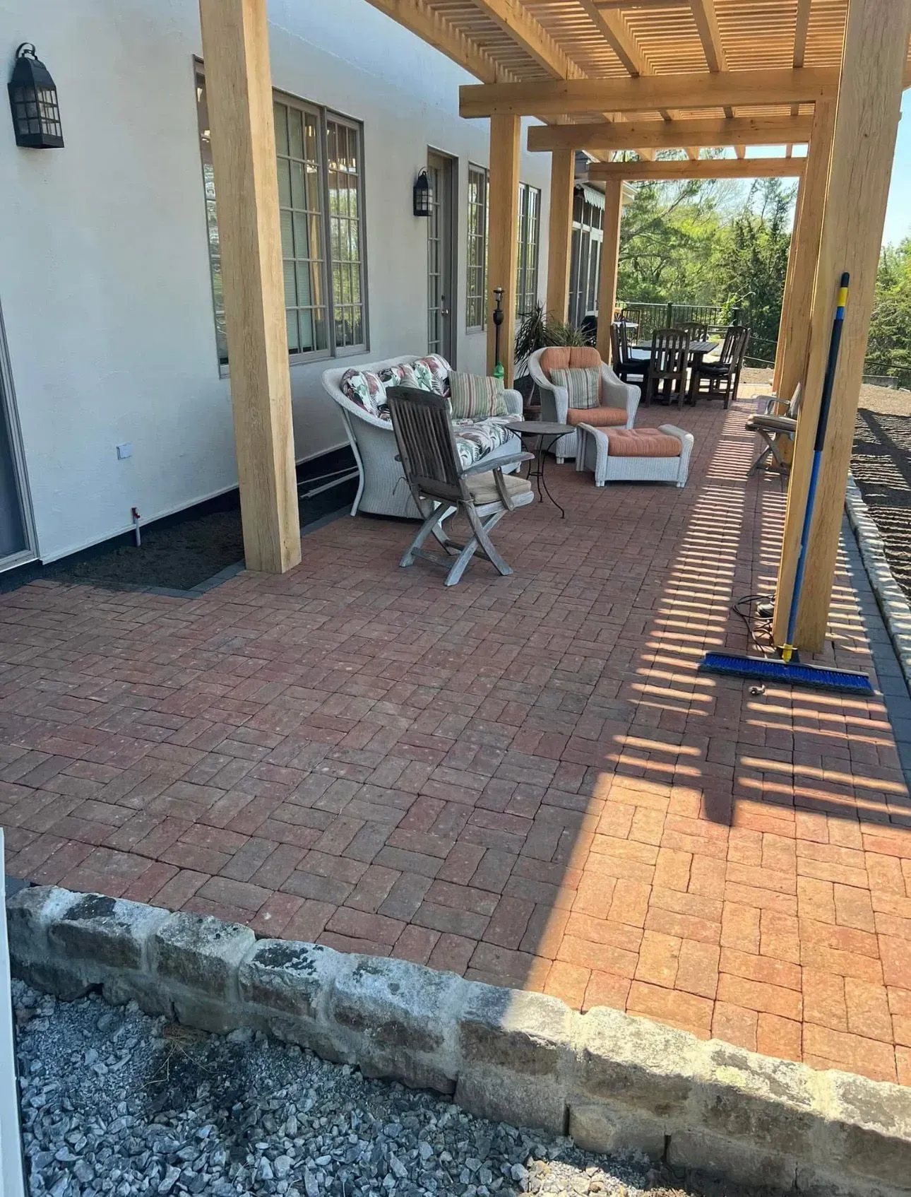 Brick patio with pergola, seating area, and building in background.