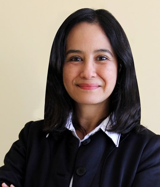 A woman in a black jacket and white shirt smiles for the camera