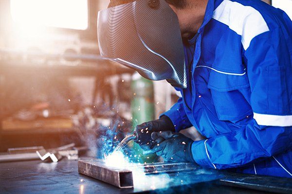 person in welding mask fabricating metal