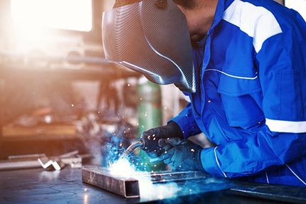 person in welding mask fabricating metal